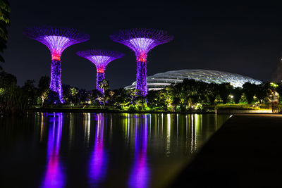 Illuminated building by river at night