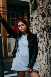 Portrait of young woman standing against wall