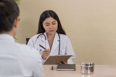Woman holding smart phone while sitting on table