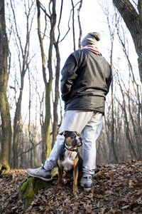 Low section of person with dog on dirt road in forest