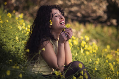 Portrait of a smiling young woman sitting by plants