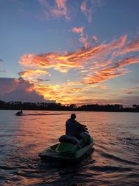 Silhouette people in boat against sky during sunset