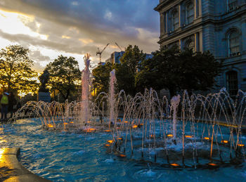 Water fountain in swimming pool against buildings