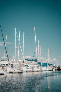 Sailboats at harbor against clear blue sky