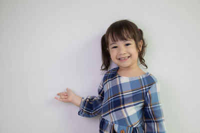 Portrait of smiling girl standing against white background