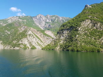 Scenic view of lake and mountains against blue sky