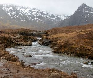 Scenic view of river and snowcapped mountains against sky