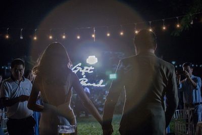 Rear view of people enjoying music concert at night