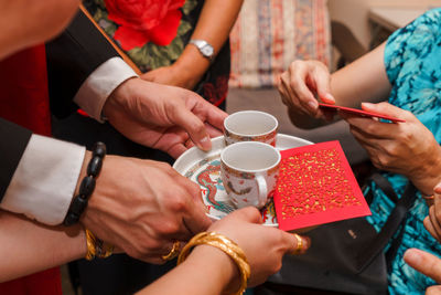 Midsection of man and woman serving coffee to relative at home