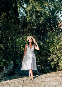 Young woman in white summer dress walking on path in city. park, greenery, lifestyle, one person.