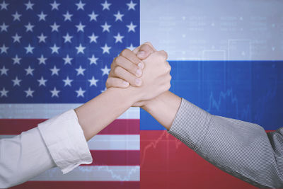 Cropped image of people holding hands against russian and american flags