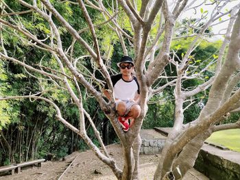 Portrait of young man standing against tree trunk