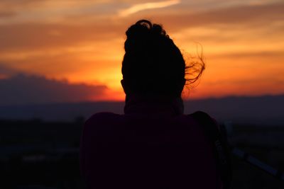 Rear view of silhouette woman against orange sky