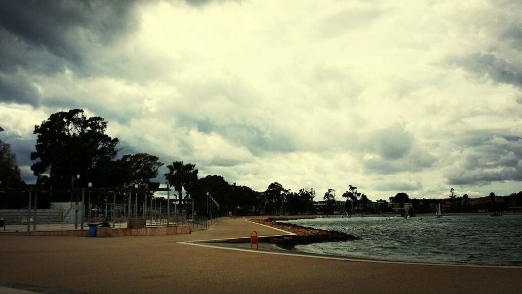 sky, beach, water, sea, cloud - sky, cloudy, tree, sand, shore, cloud, nature, scenics, tranquility, beauty in nature, incidental people, tranquil scene, horizon over water, day, built structure, outdoors