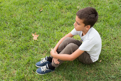 High angle view of contemplating boy sitting on grass