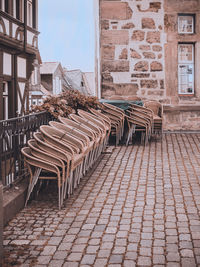 Empty chairs and tables in street against building