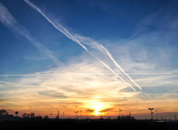 Silhouette vapor trail against sky during sunset