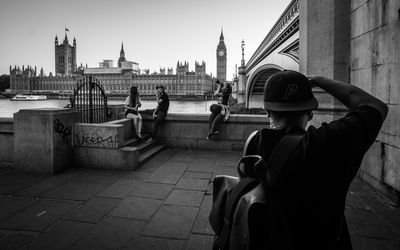 Rear view of man sitting in front of buildings