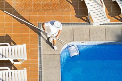 Man working in swimming pool against building