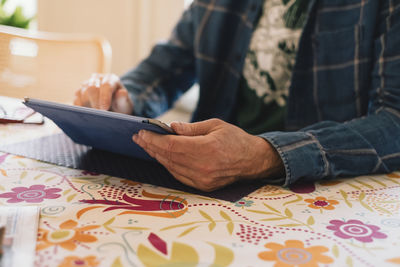Midsection of woman holding mobile phone while sitting on table