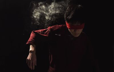 Midsection of boy standing against black background