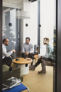 Business people seen through door while discussing with each other at office