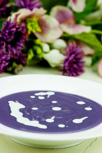 Close-up of soup served in bowl with flowers on table