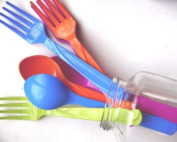 High angle view of colorful spoons and forks with jar on table