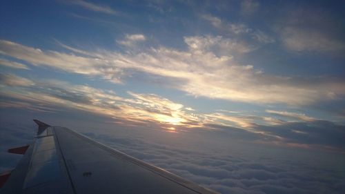 Airplane wing against sky during sunset