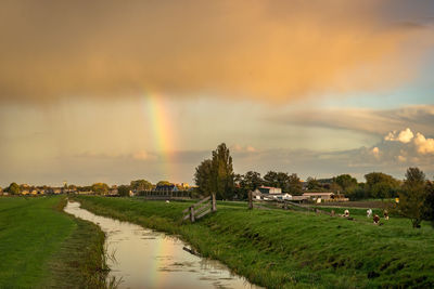 Dutch landscape with rain shower. rainbow is reflected in the water.