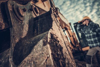 Manual worker by earth mover against sky