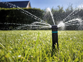 A sprinkler system watering a vibrant green lawn under the sky