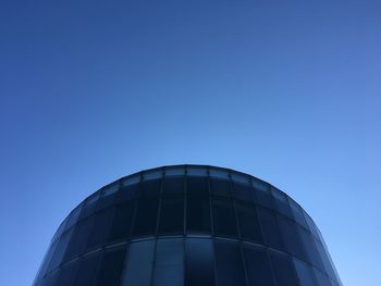 Low angle view of glass building against clear blue sky