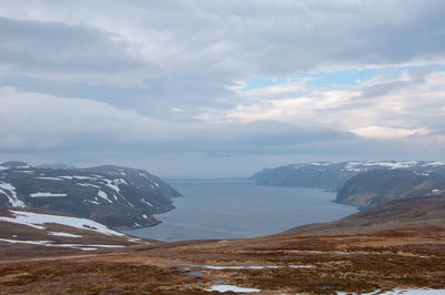Scenic view of snowcapped mountains by sea against sky