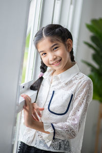 Portrait of a smiling girl standing against wall