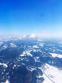 Aerial view of snowcapped mountains against blue sky