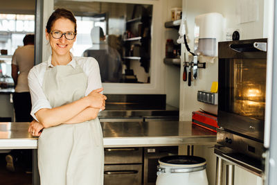 Female chef smiling at camera while standing in restaurant kitchen