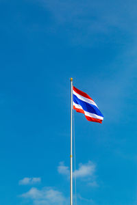 Low angle view of flag against blue sky