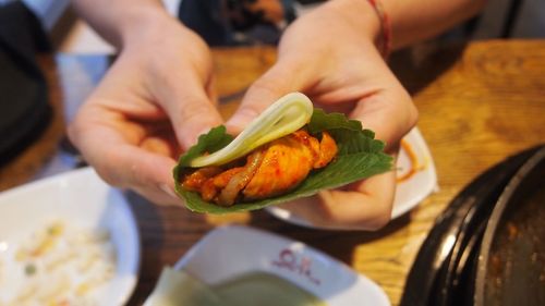 Cropped hands holding food on table at restaurant