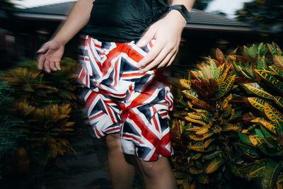 Midsection of woman holding umbrella standing by plants
