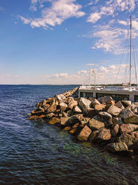 Sailboats on rock by sea against sky