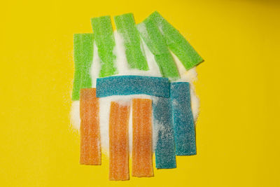 Close-up of multi colored candies against yellow background