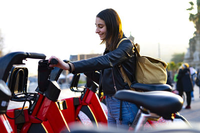 Young woman catching a red rental bike.