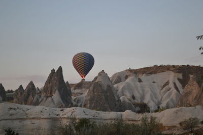 Hot air balloon flying over rocks against clear sky
