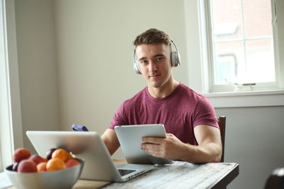 Portrait of man using mobile phone while sitting on table