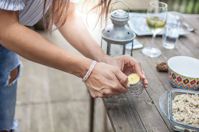 Midsection of woman igniting tea light candle