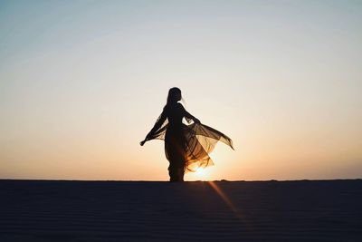 Silhouette woman standing by sea against clear sky during sunset