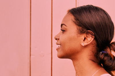 Side view of woman looking away against wall