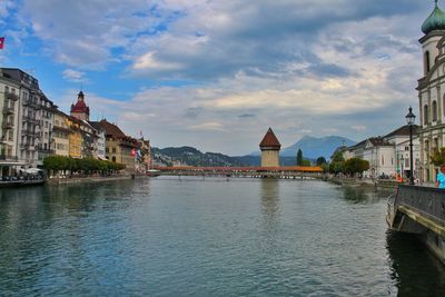 View of buildings at waterfront against cloudy sky