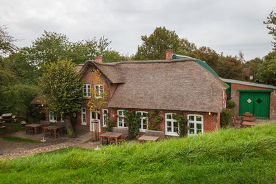 Houses in lawn by building against sky